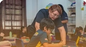 Professora acompanhando aluno em sala